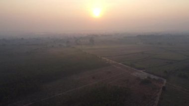 Aerial view of farmland in fog with golden sunlight at sunrise in spring. Beautiful rural landscape