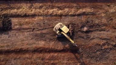 Excavator dig ground at construction site. Aerial view of a wheel loader excavator with a backhoe loading sand into a heavy earthmover. Excavator digging soil pits for the agricultural industry.