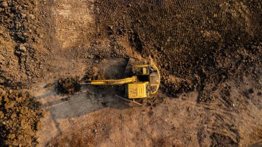 Aerial view of wheel loader excavator with backhoe unloading sand in construction site.