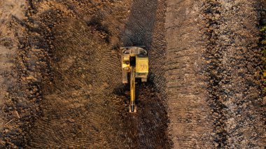 Aerial view of wheel loader excavator with backhoe unloading sand in construction site.