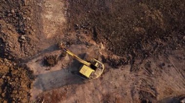 Excavator dig ground at construction site. Aerial view of a wheel loader excavator with a backhoe loading sand into a heavy earthmover. Excavator digging soil pits for the agricultural industry.
