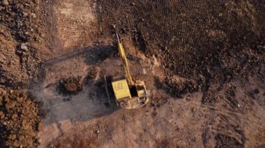Excavator dig ground at construction site. Aerial view of a wheel loader excavator with a backhoe loading sand into a heavy earthmover. Excavator digging soil pits for the agricultural industry.
