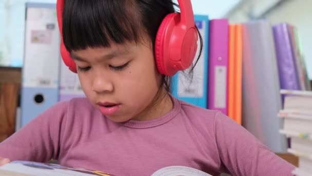Vrolijk Meisje Koptelefoon Zingen Terwijl Het Lezen Van Een Boek — Stockvideo
