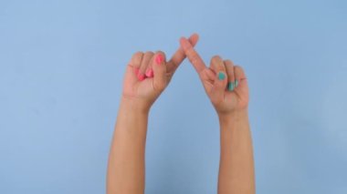 Kadın eli çapraz, stüdyodaki pastel mavisi arka planda dur işareti gösteriyor. Hareket ve vücut dili paketi.