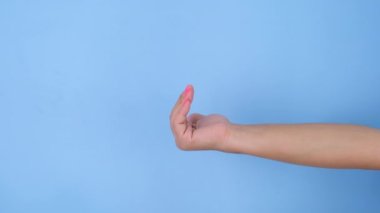 Kadın eli, stüdyodaki pastel mavisi arka plana yaklaşır. Hareket ve vücut dili paketi.