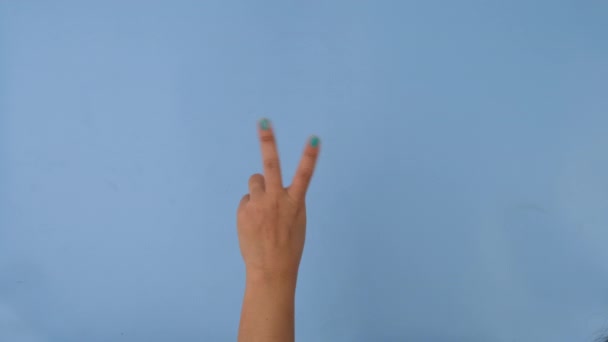 Vrouwelijke Hand Met Gebaar Van Vrede Pastelblauwe Achtergrond Verpakking Van — Stockvideo