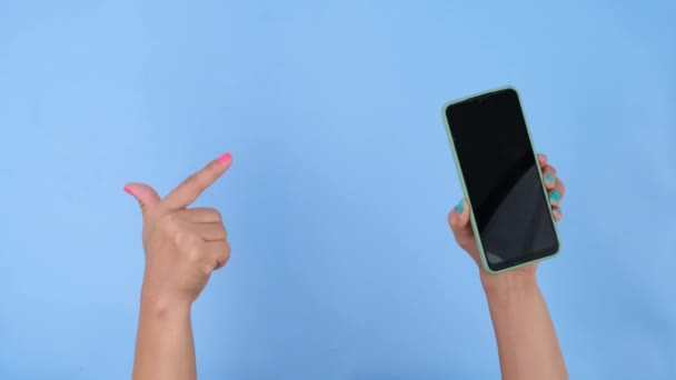 Tangan Wanita Memegang Telepon Dan Menunjuk Pada Latar Belakang Biru — Stok Video