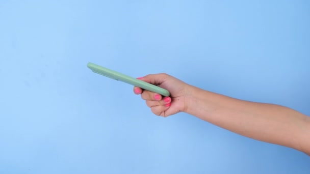 Female Hand Giving Mobile Phone Pastel Blue Background Studio — Stock Video