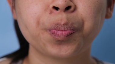 Genç bir kadın mavi arka planda sakız çiğniyor..