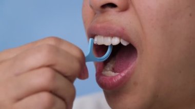 Gülümseyen Asyalı kadına yakın çekim ve mükemmel bir gülümseme için temizlik. Diş ipi, diş sağlığı ve diş bakımı ile sağlıklı beyaz dişler..