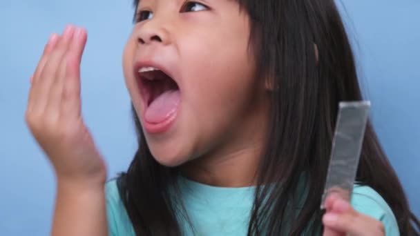 口元を覆うアジア系の少女が口臭を嗅ぐ 子供の女の子は手で息を確認します 口腔衛生の問題または歯科医療の概念 — ストック動画