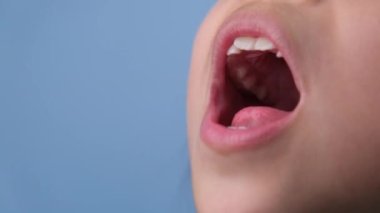 Güzel bebek dişleri olan sağlıklı bir çocuğun ağız boşluğuna yakın çekim. Genç kız ağzını açar üst ve alt dişleri, sert damak tadı, yumuşak damak, diş ve ağız sağlığı kontrollerini gösterir..