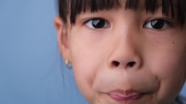 Mavi arka planda güzel beyaz dişlerini gösteren gülümseyen genç kızın yakın çekimi. Çocuklukta sağlık kavramı.