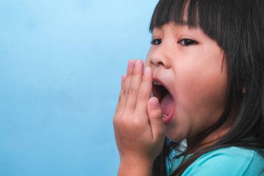 Ağzı kötü kokan Asyalı bir kız. Çocuk kız elleriyle nefesini kontrol ediyor. Oral sağlık sorunları veya diş bakımı kavramı.