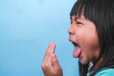 Ağzı kötü kokan Asyalı bir kız. Çocuk kız elleriyle nefesini kontrol ediyor. Oral sağlık sorunları veya diş bakımı kavramı.