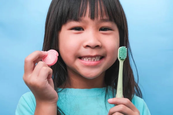 Χαμογελώντας Χαριτωμένο Κοριτσάκι Κρατώντας Οδοντόβουρτσα Και Γλυκά Απομονώνονται Μπλε Φόντο — Φωτογραφία Αρχείου