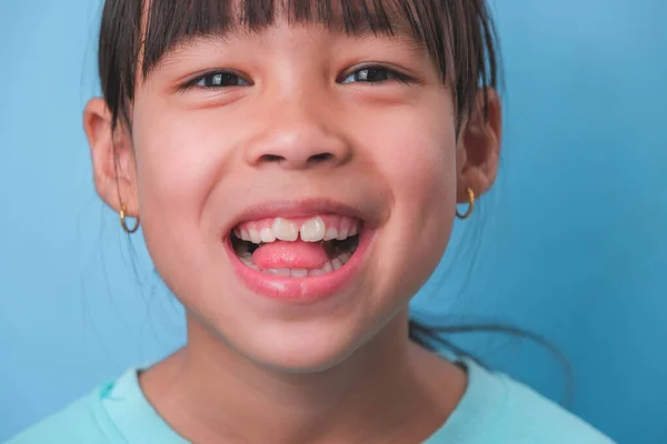 stock image Close-up of smiling young girl revealing her beautiful white teeth on a blue background. Concept of good health in childhood.