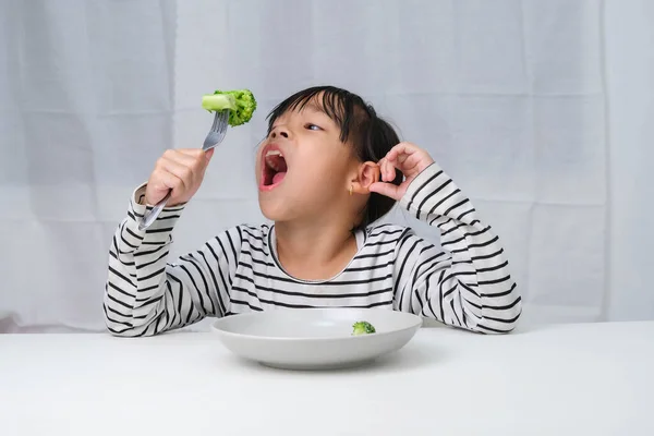 Children love to eat vegetables. Cute Asian girl eating healthy vegetables in her meal. Nutrition and healthy eating habits for children.