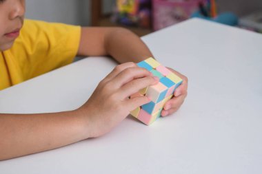 Asyalı küçük şirin kız Rubik küpünü elinde tutuyor ve onunla oynuyor. Rubik Küpü çocuklar için zekayı artıran bir oyundur. Çocuklar için eğitici oyuncaklar