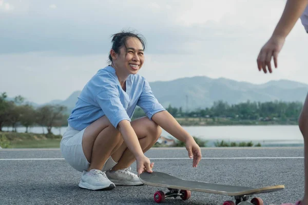 stock image Mother teaching her daughter how to skateboard in the park. Child riding skate board. Healthy sports and outdoor activities for school children in the summer.