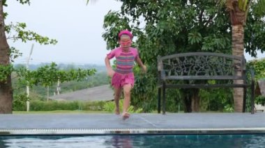 Gözlüklü tatlı kız havuza atlıyor. Küçük kız yüzüyor ve suda oynuyor. yaz tatili konsepti.