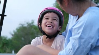 Anne ve çocuklar parkta scooterlara bindikten sonra oturup dinlenirler. Anne ve kızları boş zamanlarını dışarıda motosiklet sürerek geçiriyorlar. Mutlu Aile Sevgisi.