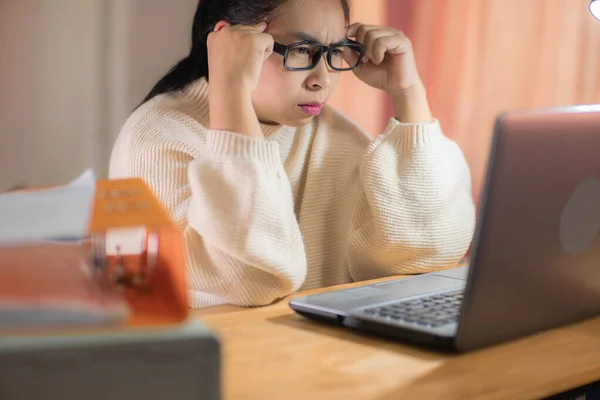 Stressed woman working with laptop in office at home. Busy businesswoman in glasses using laptop sitting in office and doing research.
