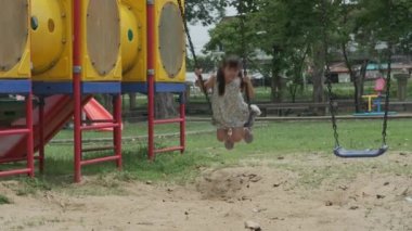 Mutlu kız salıncakta eğleniyor. Küçük Asyalı kız yaz tatilinde parkta oyun oynuyor. Sağlıklı etkinlik.