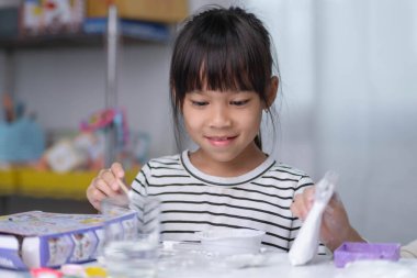 Şirin küçük kız evde boya ve boya yapıyor. Çocuklar tatilde aileleriyle alçı heykellere resim yaparlar. Hayal gücü ve yaratıcılık faaliyetleri.