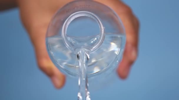Mano Sosteniendo Botella Agua Vertiendo Aislado Sobre Fondo Azul Verter — Vídeo de stock