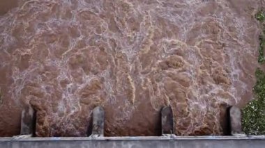 Beton barajın drenaj kanalından fışkıran suyun hava görüntüsü yağmur mevsiminde taşan suyun bir yoludur. Turbiş kahverengi orman sularının en üst görüntüsü Tayland 'daki bir barajdan akıyor..