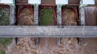 Beton barajın drenaj kanalından fışkıran suyun hava görüntüsü yağmur mevsiminde taşan suyun bir yoludur. Turbiş kahverengi orman sularının en üst görüntüsü Tayland 'daki bir barajdan akıyor..