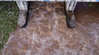 Beton barajın drenaj kanalından fışkıran suyun hava görüntüsü yağmur mevsiminde taşan suyun bir yoludur. Turbiş kahverengi orman sularının en üst görüntüsü Tayland 'daki bir barajdan akıyor..