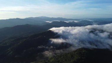 Mavi gökyüzünde sabah güneşinde sisli bir denizle dağların üzerinden hava manzarası. Gün doğumunda dağların etrafındaki bulutlar denizi. Kuzey Tayland 'da görülmemiş seyahat