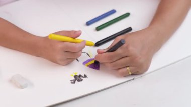 Anne ve kızı pastel boyalarla birlikte çiziyorlar. Yetişkin bir kadın, kızın evde ders çalışmasına ya da resim yapmasına yardımcı olur. Mutlu aile.