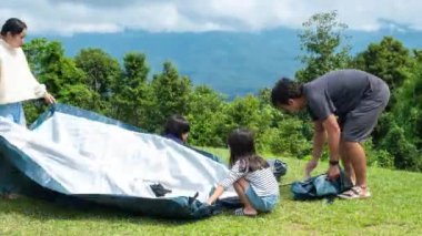 Küçük kızları olan mutlu bir aile kamp çadırı kuruyor. Mutlu çocukluk, ailenle kamp gezisi. Hafta sonu dağın tepesinde mutlu bir aile..