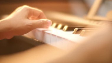 Genç bir kadının piyano çalarkenki görüntüsü. Mutlu Asyalı kadın piyano öğreniyor ve pratik yapıyor. Seçici odak.