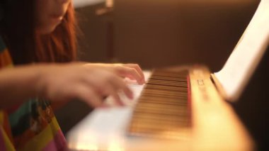 Kızıyla piyano çalan genç bir kadının ellerinin yakın çekimi. Mutlu Asyalı kız annesine öğretiyor ve piyano çalışıyor. Seçici odak.