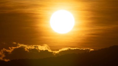 Sakin bir akşamda, turuncu renkli parlak güneşin gökyüzüne yakın çekim.