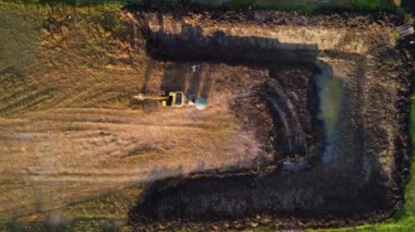 Kurak mevsimde tarım için kullanılmak üzere bir su birikintisi inşa etmek için bir çöp kamyonuna toprak kazmak. Bir kepçenin havadan görünümü işe yarıyor.