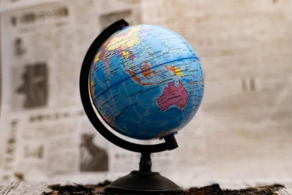 Model globe on a newspaper in the background.