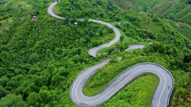 Ormanın ortasındaki bir yolun havadan görünüşü, Kuzey Tayland 'da dağlarda kıvrımlı bir yol inşaatı..