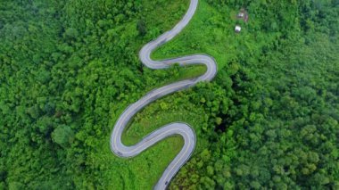 Ormanın ortasındaki bir yolun havadan görünüşü, Kuzey Tayland 'da dağlarda kıvrımlı bir yol inşaatı..