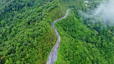 Ormanın ortasındaki bir yolun havadan görünüşü, Kuzey Tayland 'da dağlarda kıvrımlı bir yol inşaatı..