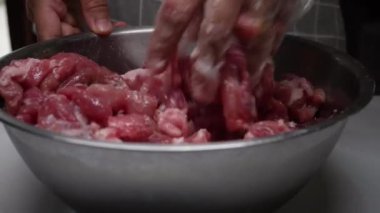 Genç kız, annesinin sukiyaki için kullanılan bir kasede çiğ domuz eti pişirmesine yardım ediyor..