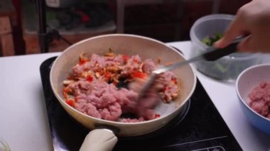 Genç kadın mutfakta fesleğenli kızarmış domuz kıyması yapıyor, adım adım pişiriyor..