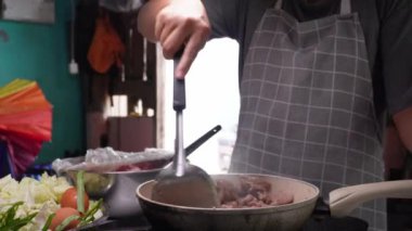 Genç bir kadın mutfakta adım adım domuz sukiyaki pişiriyor..