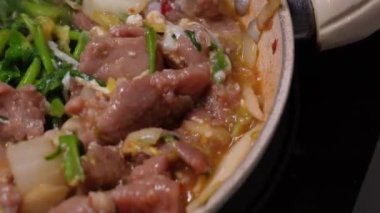 Genç bir kadın mutfakta adım adım domuz sukiyaki pişiriyor..