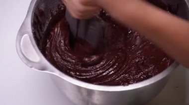 Genç kadın mutfakta ev yapımı brovni yapıyor, adım adım pişiriyor..