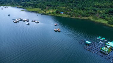 Kwai Nehri 'nin havadan görünüşü ve Kanchanaburi Eyaleti, Tayland' da yüzen evler. Yüzen kulübelerin ve Kwai Nehri üzerinde yüzen Tayland uzun kuyruklu teknelerinin güzel manzarası..